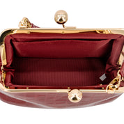 Close-up of the interior of a Wine crocodile-embossed handbag with a gold-tone kiss-lock frame and matching burgundy satin lining.