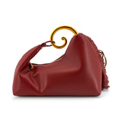 A red leather shoulder bag with a gold-tone spiral handle and a fringed strap detail, shown on a plain white background.
