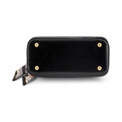 Black leather wallet or clutch with gold-tone metal studs and a small patterned scarf tied to the side, shown on a plain white background.