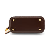 A dark brown leather zip-around wallet or clutch shown from the bottom, featuring four gold-tone metal studs and a small patterned fabric pull tab on the left side, set against a plain white background.