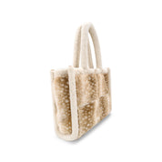 A small plush tote bag with a soft patchwork design in beige and cream, featuring cream-colored handles and trim, shown on a plain white background.