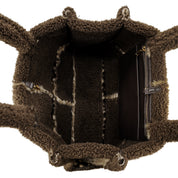 The interior of a brown teddy fleece tote bag, showing the lining, zippered compartments, and side handles against a white background.