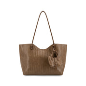 A brown woven leather tote bag with a single shoulder strap and a matching leather hanging charm, shown against a plain white background.