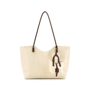 A Ivory-colored textured leather tote bag with dark brown shoulder straps and a matching hanging leather charm, shown against a plain white background.
