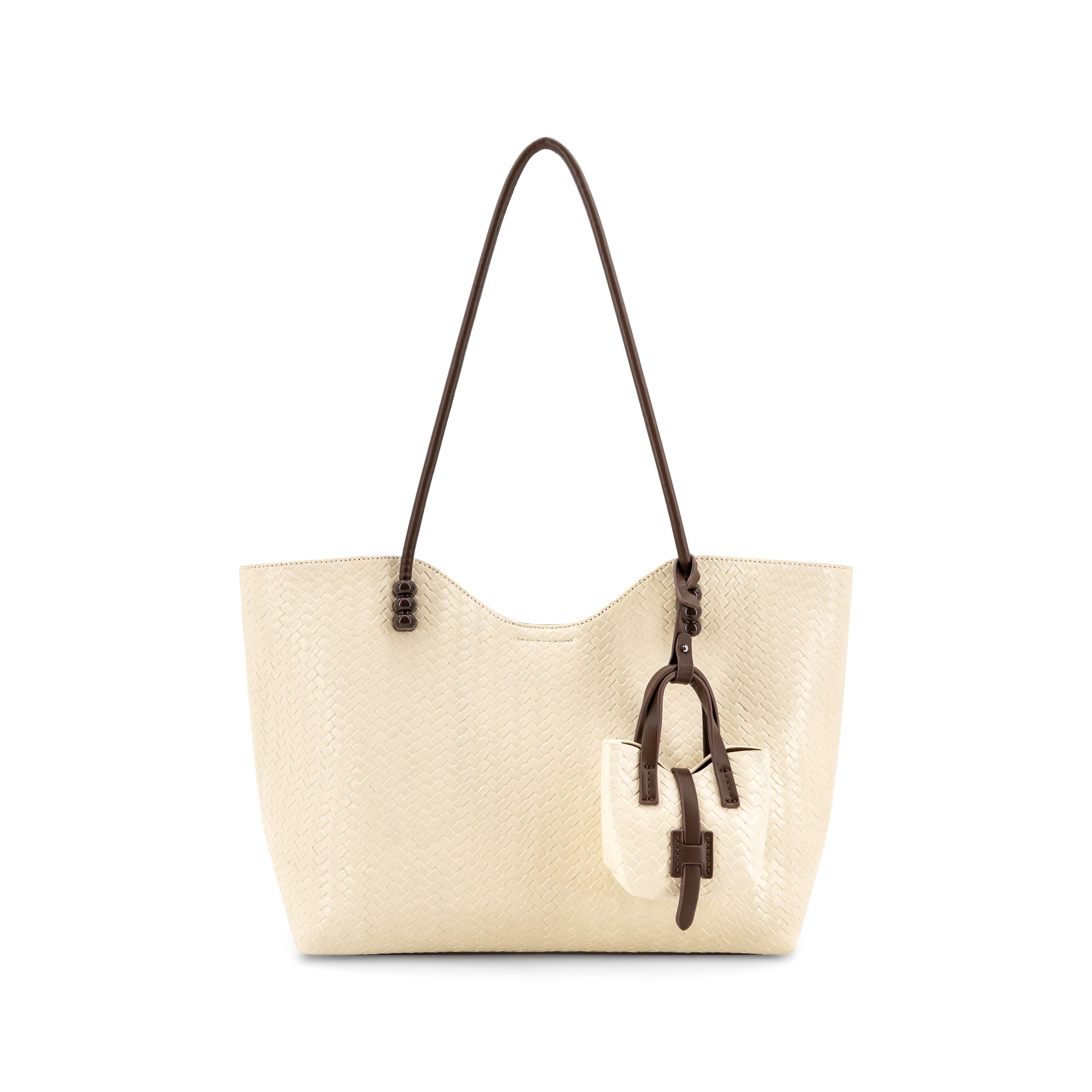 A Ivory-colored textured leather tote bag with dark brown shoulder straps and a matching hanging leather charm, shown against a plain white background.